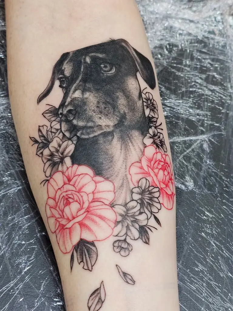 Tatuaje realista de perro con rosas rojas en el antebrazo, Bendito Querer (La Laguna, Tenerife)